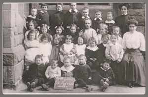 Parkgate Infant School, 1910 Back Row: the teacher far right is Miss Catherine Norman (David Scott's mother), Jim Bushell is standing next to her, far left is Monty Smith and third left is one of the Fewtrells. Next Row: Lizzie Bushell is the tall girl fifth on the left, next right is one of the Higgins', then Eva Bushell and teacher Miss Annie Bushell of Neston. Next Row: third from the left is Bet Fewtrell and next right is Mollie Bushell.